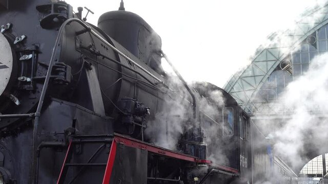 A retro steam locomotive prepares to leave the station.
