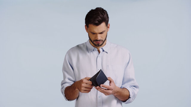sad man looking at empty wallet isolated on blue