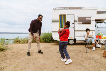 Black family playing with rugby ball during journey on trailer