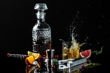 The glass of cognac or brandy isolated on a black background. alcohol cocktail. ice cubes fall into...