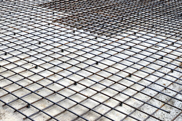 Iron reinforcement in the form of a grid on a concrete foundation.