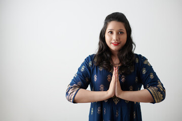Portrait of positive Indian woman making namaste gesture and looking at camera