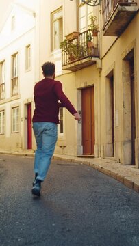 Vertical Screen: Cheerful Young Adult Man in Casual Clothes Actively Dancing while Walking on the Street of an Old Town in a City. Scene Shot in an Urban Environment on an Quiet Small Town Street.