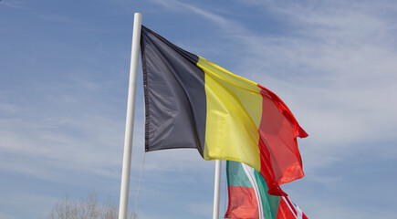 National flag of Belgium against the background of the blue sky.