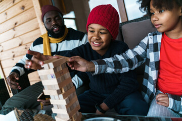 Black boys playing jenga game while sitting with their father