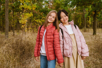 Fototapeta premium Multiracial teenagers holding hands during hiking in autumn forest