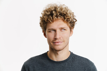 Young blonde man with curly hair smiling and looking aside - obrazy, fototapety, plakaty