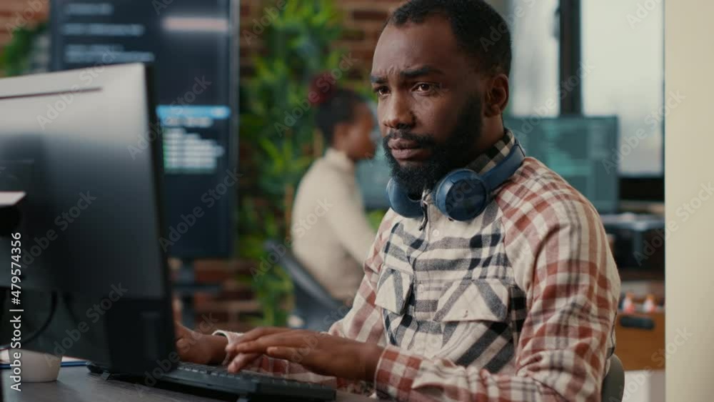 Wall mural portrait of focused african american programer wearing wireless headphones working looking at comput