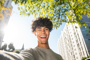 happy young man taking selfie outside in city