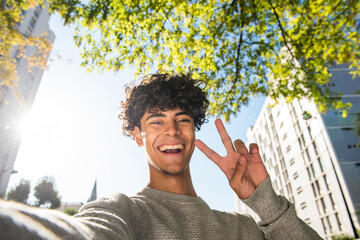 handsome young man taking selfie with hand peace sign