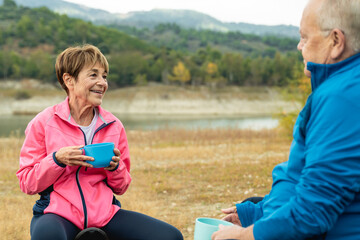 Happy senior couple having fun camping together outdoor in mountain lake - Elderly travel vacation