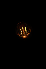 Classic Edison light bulb on black background with space for text