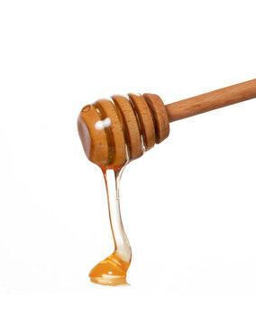 Wood honey dipper straining honey on white background.