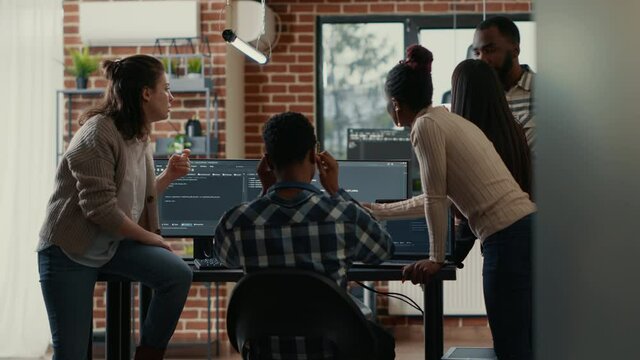 Coders discussing about source code compiling discovers errors and asks the rest of the team for explanations in front of multiple screens running algorithms. Software developers doing teamwork.