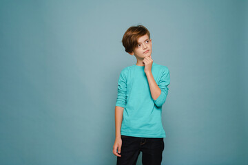 Ginger puzzled boy wearing long sleeve posing and looking aside