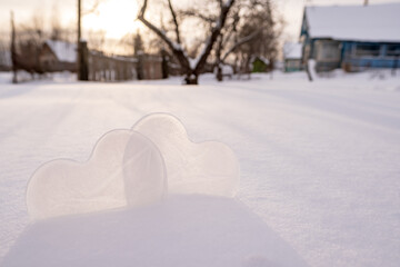 Two hearts - a symbol of love, made of ice, in a snowdrift, in a village courtyard. Valentine's Day. Romantic concept. Copy space.
