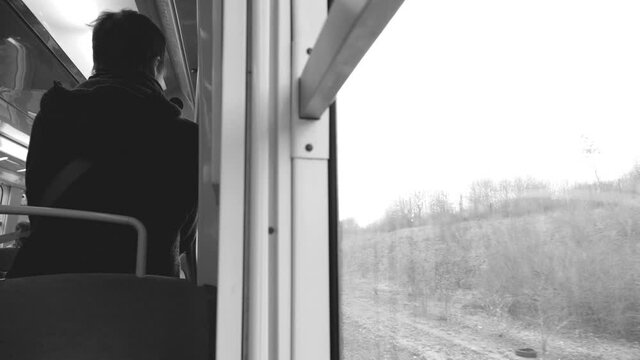 Black and white HD slow-motion scene rear view of unrecognizable man traveling alone in RER French train 