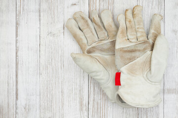 Dirt covered leather work gloves on weathered wood