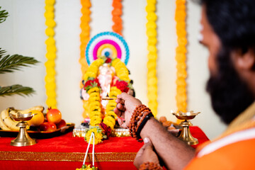 Focus on hand, shoulder shot of saint, god man offering mangalaarthi to lord ganesh idol during...