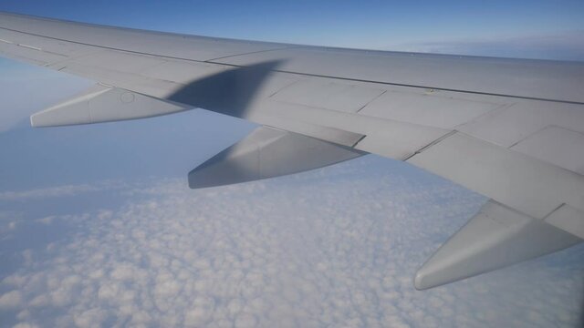 A view of a plane wing flying over clouds.