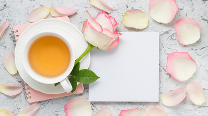 Blank sheet paper for text with rose, petals and cup of tea. Banner with copy space paper for congratulation, greeting, mockup and design