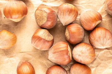 Several unpeeled hazelnuts on craft paper, close-up, top view.