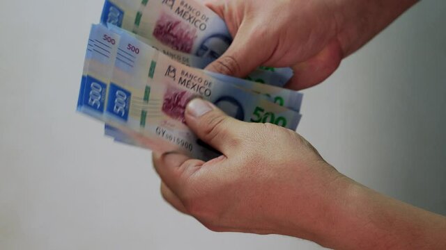 Hombre cuenta dinero en efectivo billetes de 500 pesos mexicanos contando con manos 