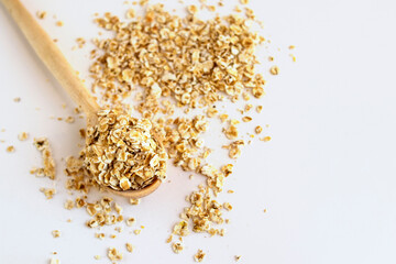 Oatmeal breakfast cereal with wooden spoon on white background macro
