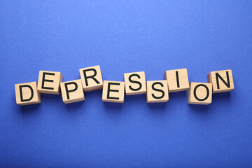 Word Depression made of wooden cubes on blue background, flat lay