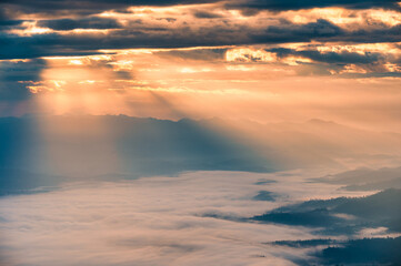 Naklejka na ściany i meble Sunbeam shining through cloudy over Doi Luang Chiang Dao mountain and foggy in the morning