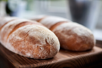 Freshly baked homemade wheat loaves on wooden background. Close-up, selective focus