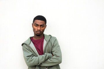 handsome young black man posing with arms crossed by white background