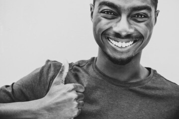 Close up black and white smiling young black man with thumbs up hand sign