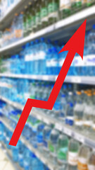 Red growing up arrow on abstract blur image of supermarket background. Bar charts and graphs. Rising food prices. Inflation concept. Retail industry. Finance and Economy. Shelves with bottles water.