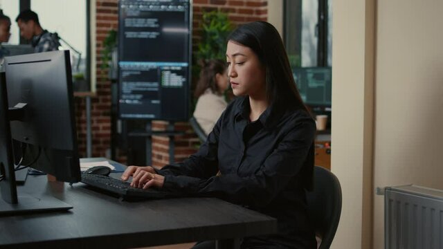 System engineer focused on writing code sitting at desk in software development office while team of coders are developing cloud computing app. Programer concentrating on creating algorithm.