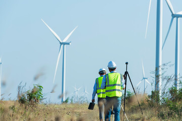 Two Service engineers walking and holding the equipment to  at wind turbine farm Power Generator...