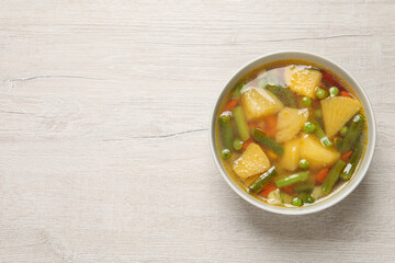 Bowl of delicious turnip soup on wooden table, top view. Space for text