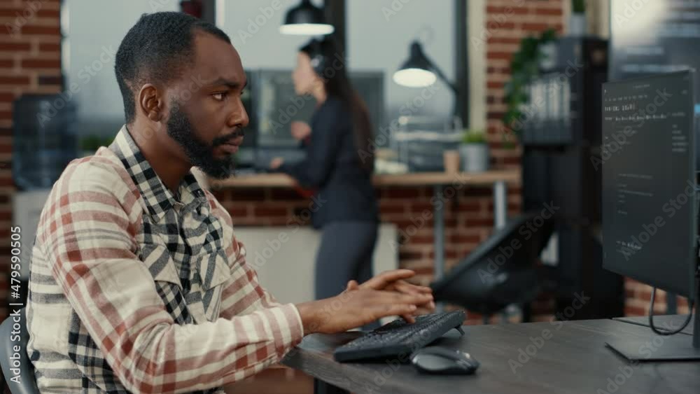 Wall mural static portrait of african american system engineer working focused looking at computer screen while