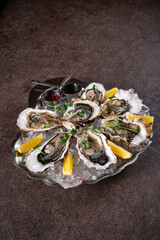 Raw open oysters on metal plate with ice and lemon