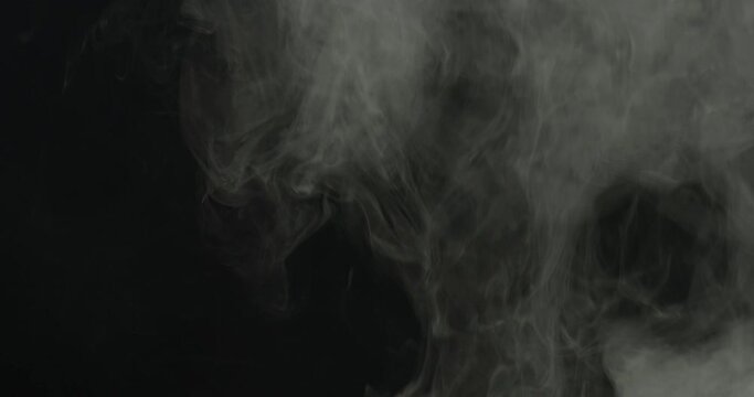 Realistic atmospheric gray smoke on black background. White fume slowly floating rises up.
