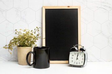 Composición de mesa de trabajo con una pizarra, un reloj despertador y una taza de café. Vista de...