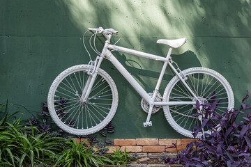 White bicycle is on a green wall background outside