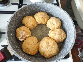 Chicken cutlets with carrots are fried in a pan