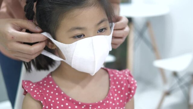 Mother Putting Protective Face Mask On Her Child , Prevent Covid19 And Pm2.5 Concept.