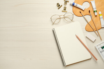 Flat lay composition with blank sketchbook on white wooden table. Space for text