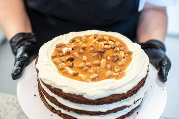 Pastry chef cook confectioner or baker in black gloves and black kitchen apron makes a cake. Home made birthday cake. Concept of homemade pastry, cooking cakes, hobby. Female small home business