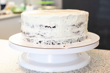 Pastry chef cook confectioner or baker in black gloves and black kitchen apron makes a cake. Home made birthday cake. Concept of homemade pastry, cooking cakes, hobby. Female small home business.
