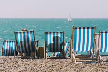 Beach chairs on the beach with a sailboat in the background
