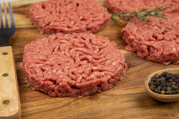 several raw hamburgers on a cutting board