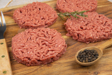 several raw hamburgers on a cutting board
